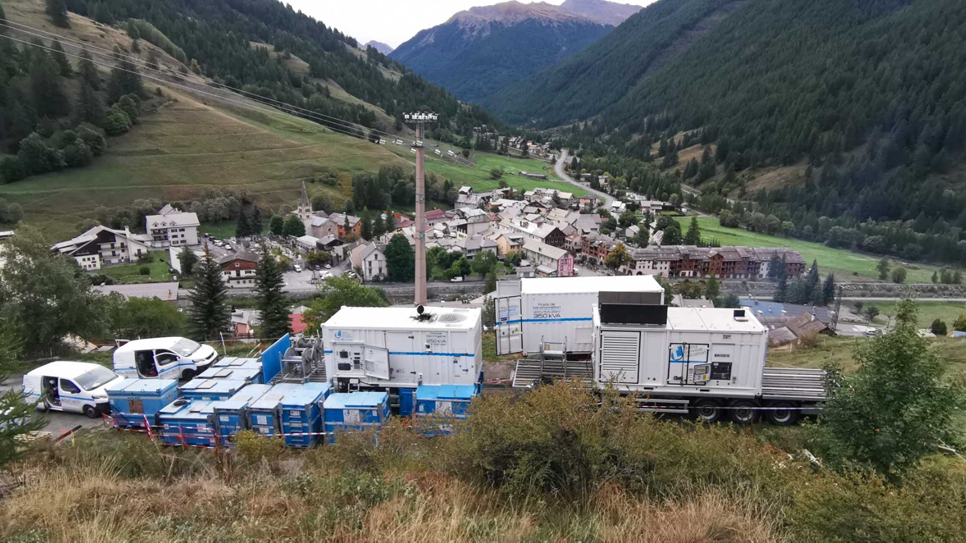 Groupes électrogènes et cuves aux abords d'un pilonne électrique avec la vue sur la vallée